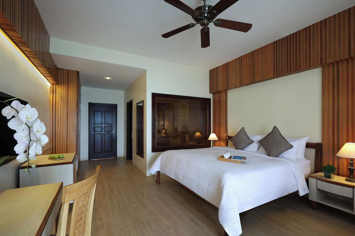 Ein Hotelzimmer mit einem großen Bett, einem Deckenventilator, Holzverkleidung, einem Schreibtisch und einem Stuhl.