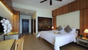 A hotel room with a large bed, a ceiling fan, wooden paneling, a desk, and a chair.