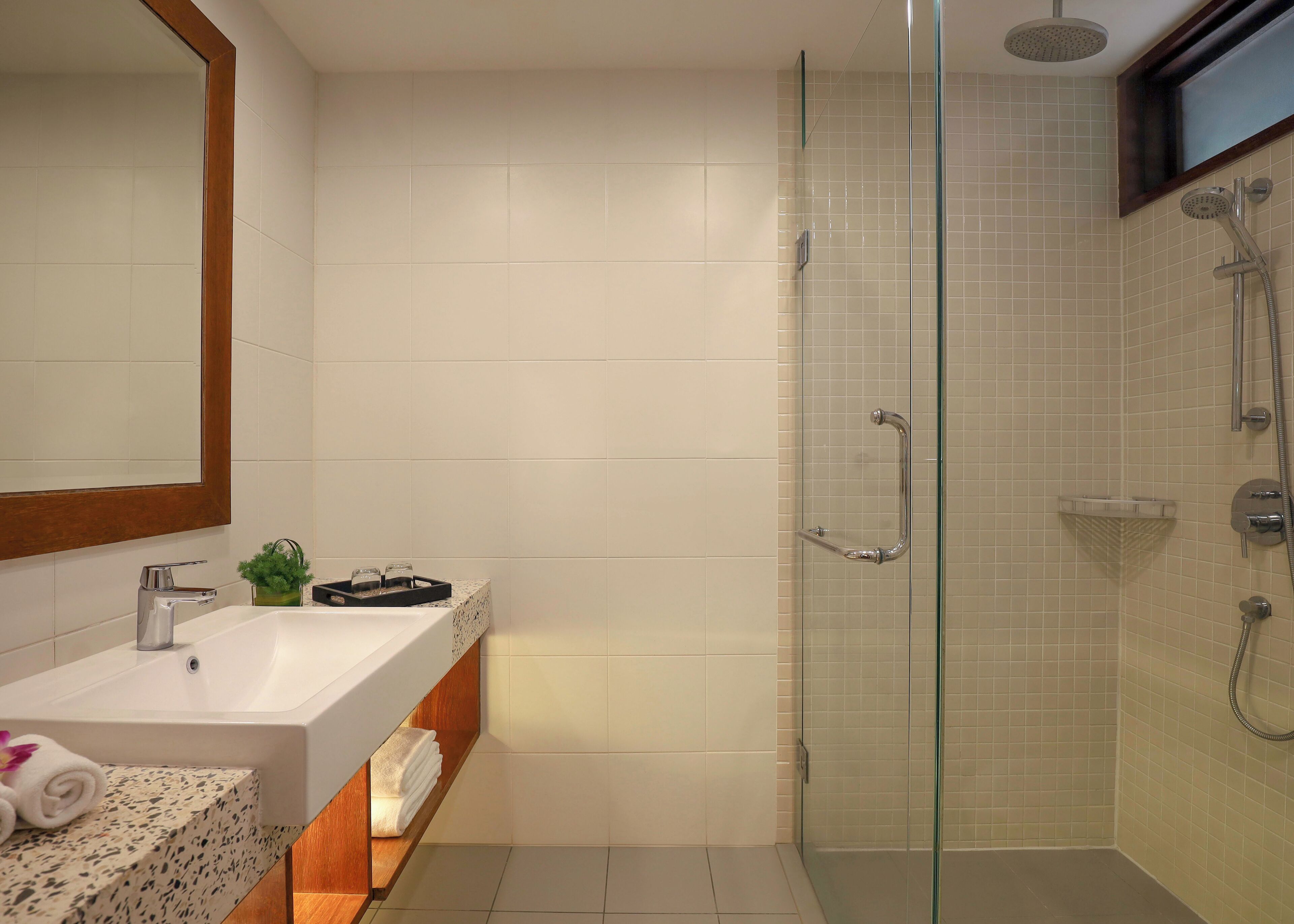 A modern bathroom with a glass-enclosed shower, a white sink, and a mirror.