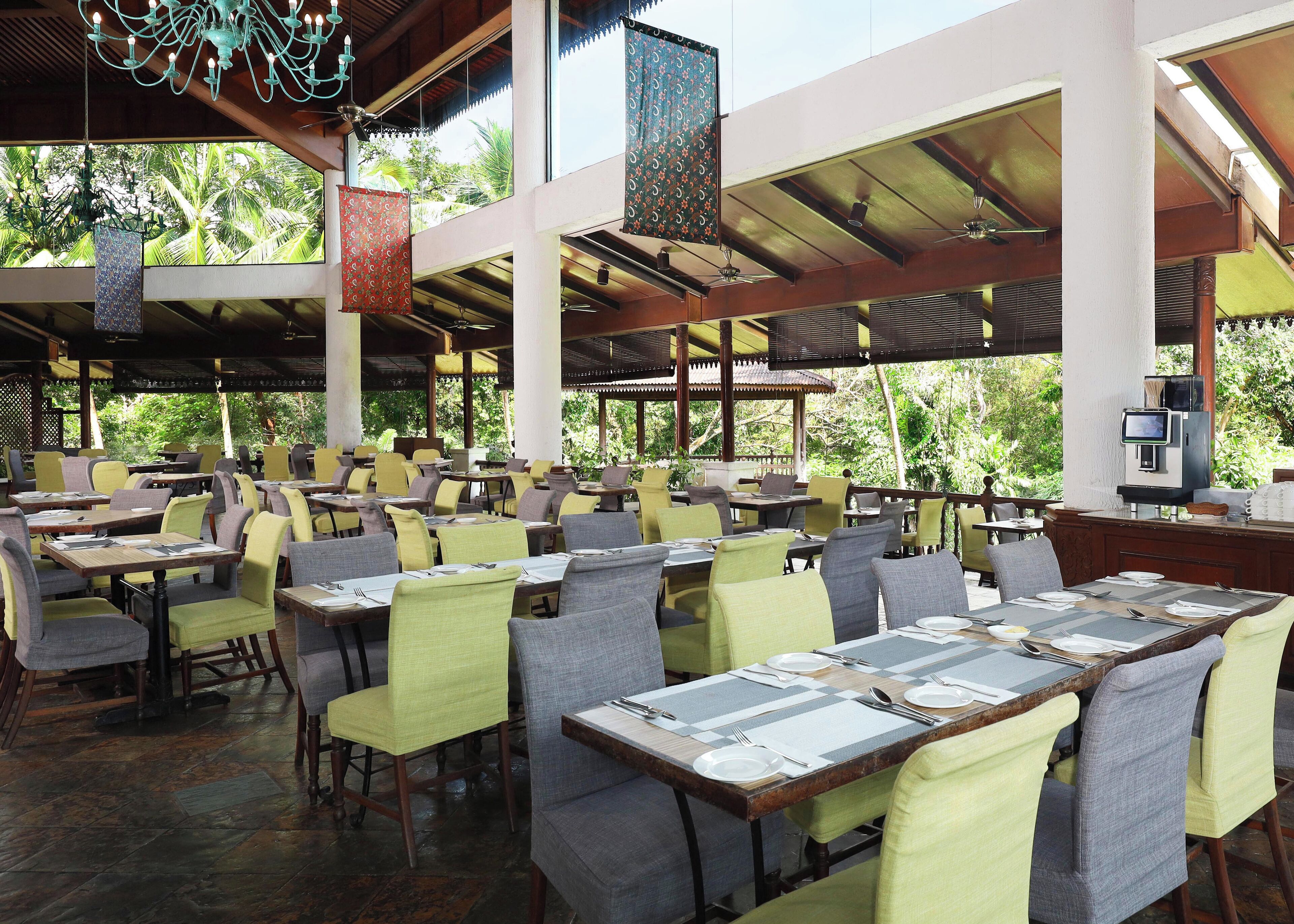 A spacious outdoor restaurant with multiple tables and chairs, large windows, and a ceiling fan.
