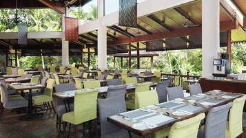 A spacious outdoor restaurant with multiple tables and chairs, large windows, and a ceiling fan.