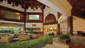 A spacious lobby with high ceilings, wooden beams, and a central fountain. There are multiple seating areas with wicker furniture and potted plants. - Berjaya Langkawi Resort (Langkawi)