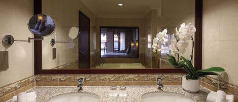 A bathroom with two sinks, a large mirror, and a potted orchid.
