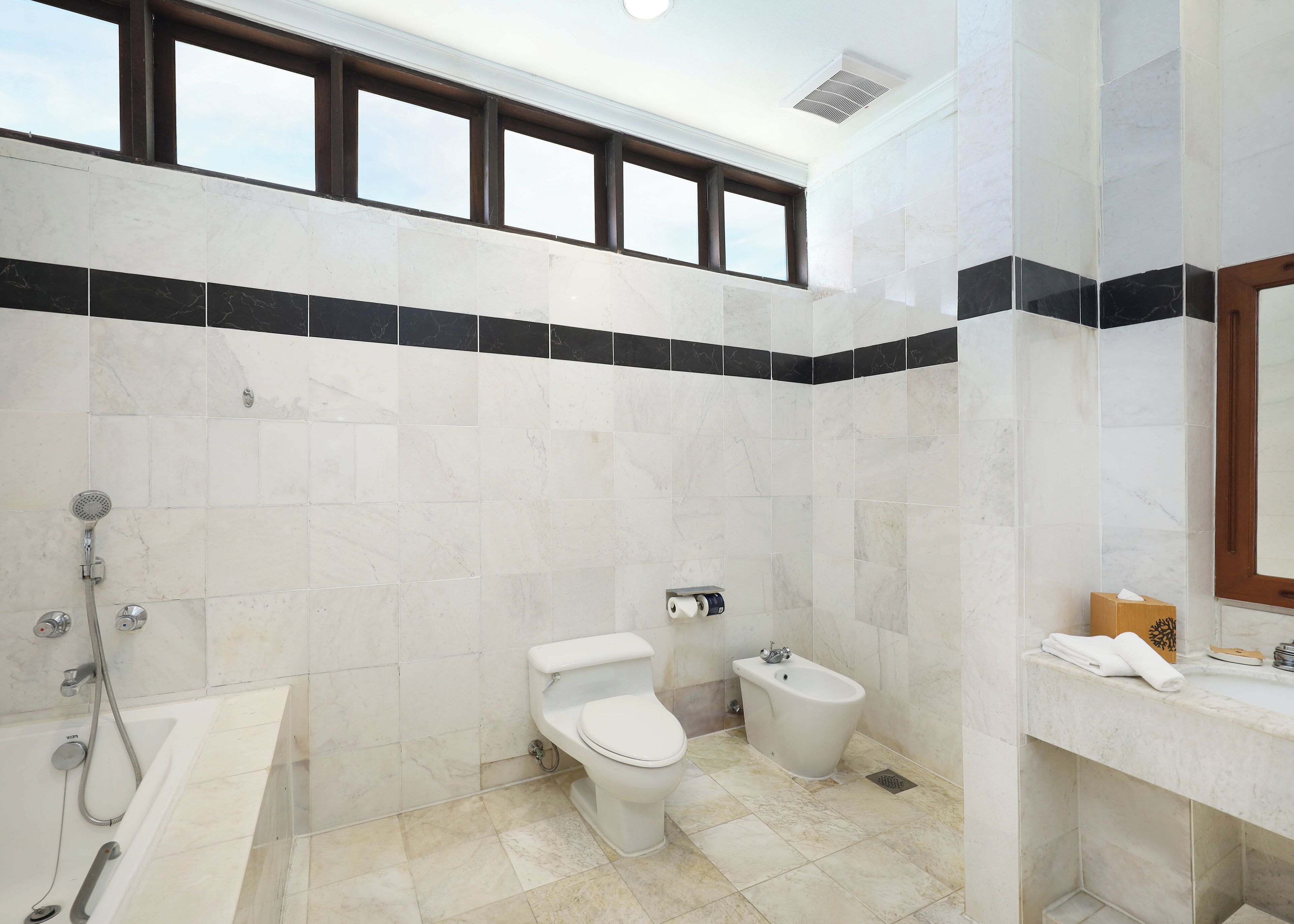 Ein modernes Badezimmer mit Badewanne, Toilette, Bidet und einem Waschtisch mit Spiegel.