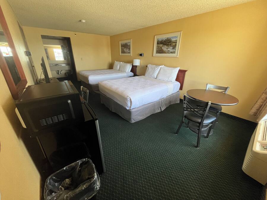 Ein Hotelzimmer mit zwei Betten, einem Schreibtisch, einem Stuhl, einem Tisch und einer Mülleimer.