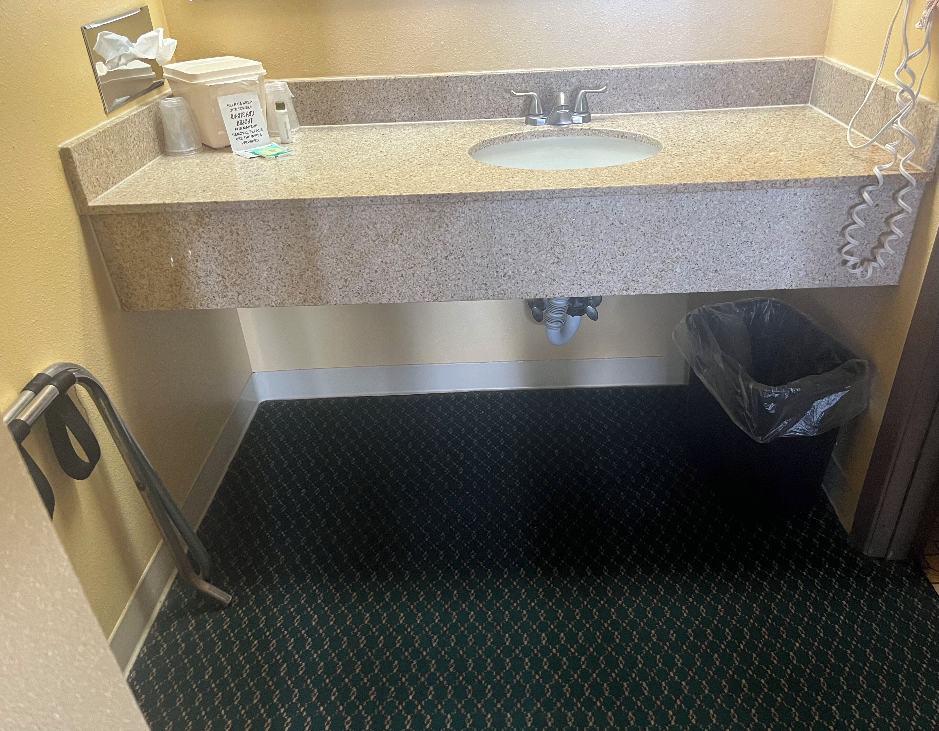 Une salle de bain avec un comptoir en granit, un lavabo, une poubelle et un sèche-mains.