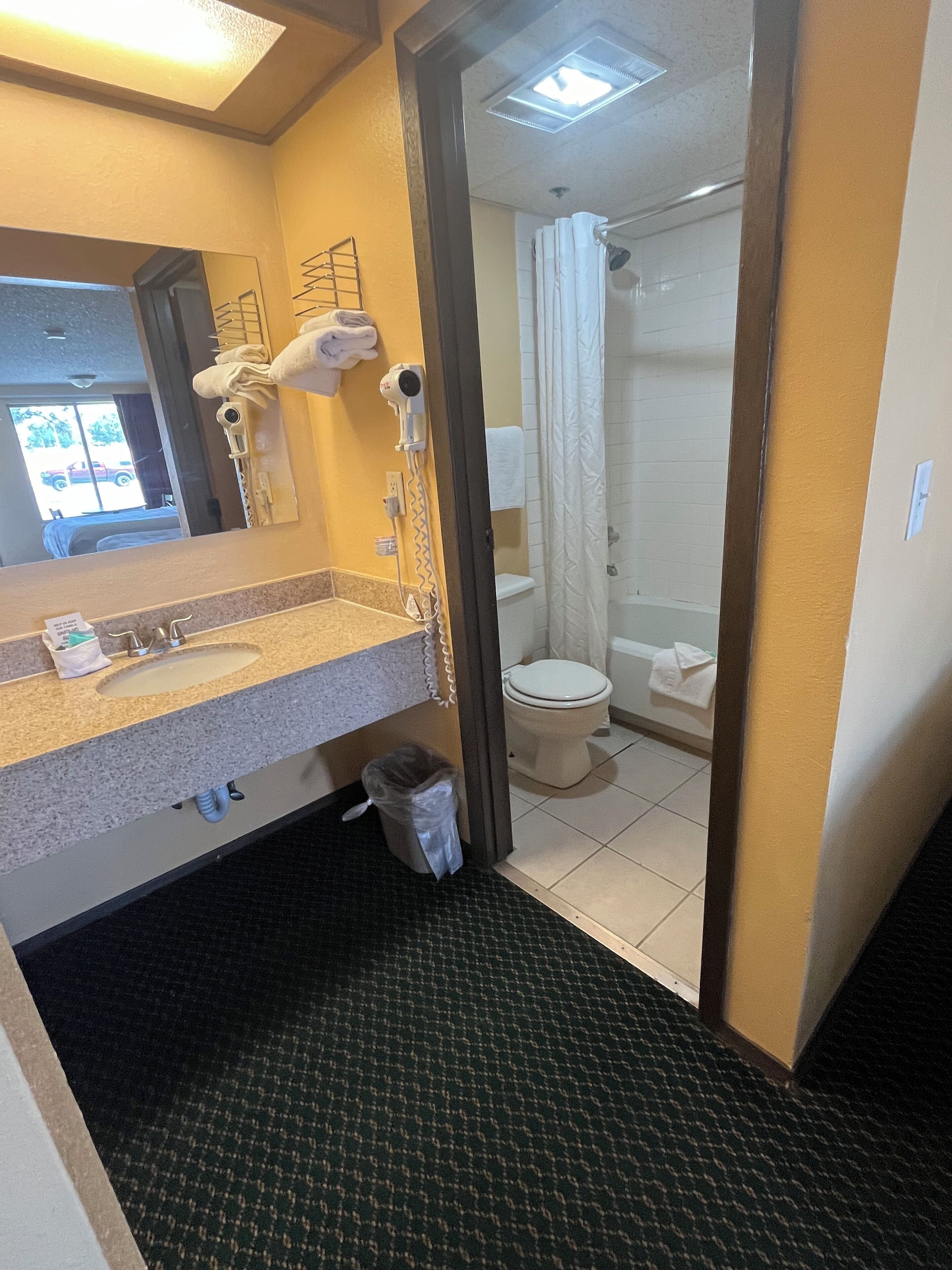 A hotel bathroom with a sink, toilet, and shower.