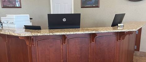A reception desk with a laptop, a printer, and framed pictures on the wall.