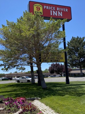 A Price River Inn sign with a National 9 Inn logo, a parking lot, and a tree.