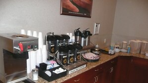 A coffee station with a coffee machine, coffee pods, and a sign reading "Fresh Hot Coffee". - National 9 Price (Price)