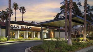 A Courtyard by Marriott hotel entrance with a covered walkway, palm trees, and well-lit exterior. - Courtyard by Marriott Los Angeles Torrance Palos Verdes (Torrance)