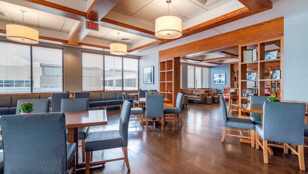 A spacious indoor area with wooden beams, tables, and chairs arranged for dining or meetings.
