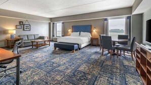 A hotel room with a large bed, a sofa, a desk, and a TV.