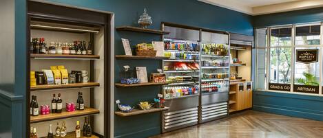 A store with shelves of beverages, a sign reading 'GRAB & GO,' and a window with 'ARTISAN' signage.