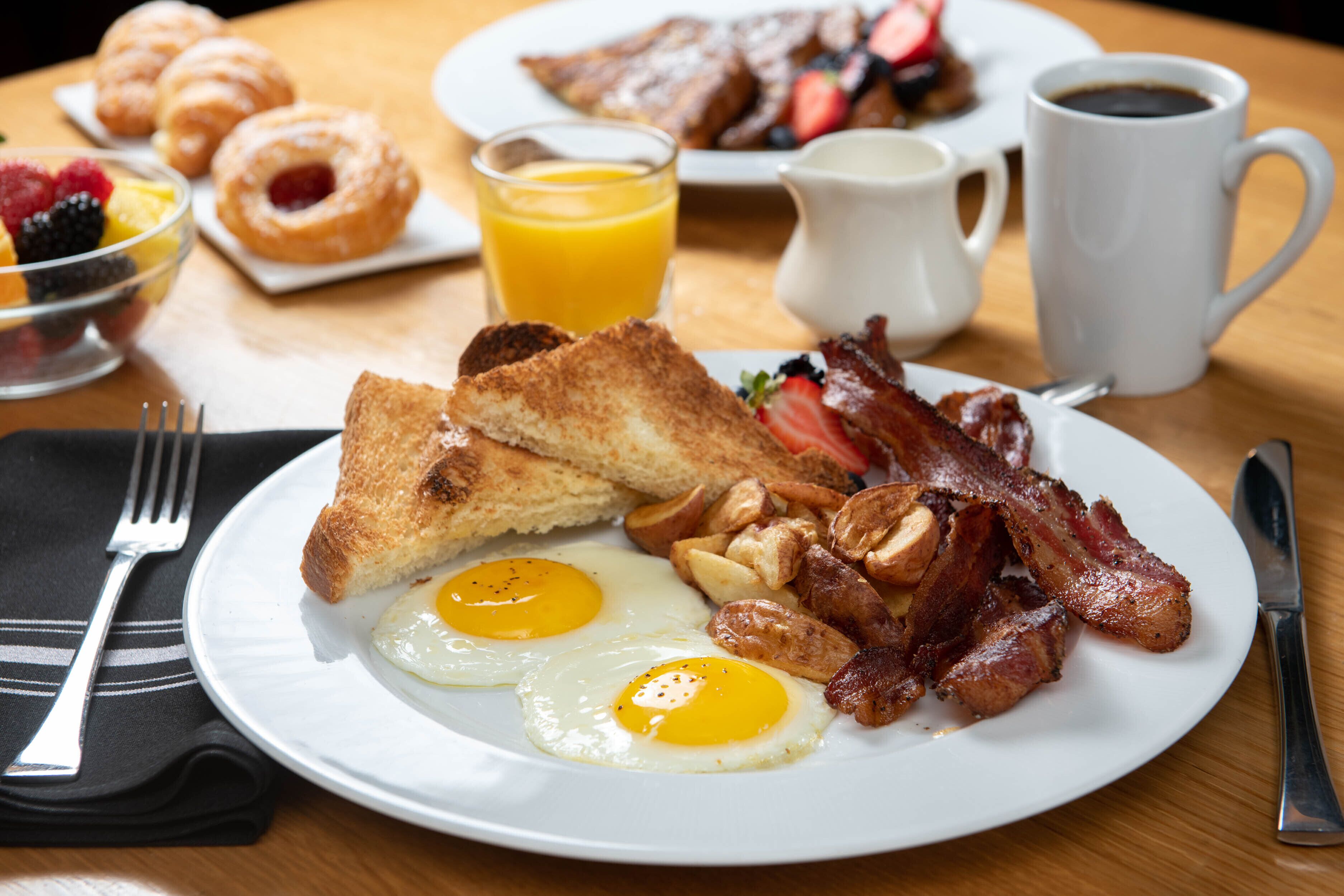 A breakfast plate with eggs, bacon, toast, and sausage.