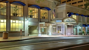 A hotel entrance with a modern design, featuring a prominent 'Hilton' sign, a flag, and a well-lit facade. - Hilton Portland Downtown (Portland)