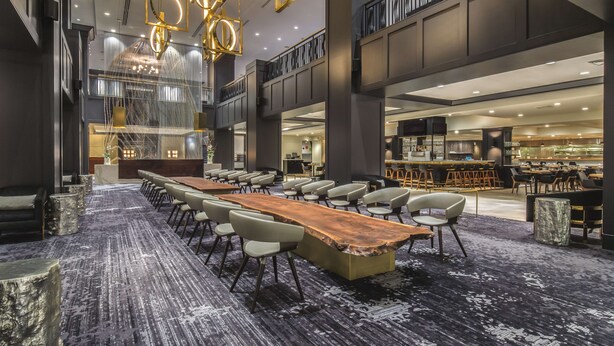 A spacious conference room with a long wooden table, modern chairs, and a high ceiling with unique lighting fixtures. - Hilton Portland Downtown (Portland)
