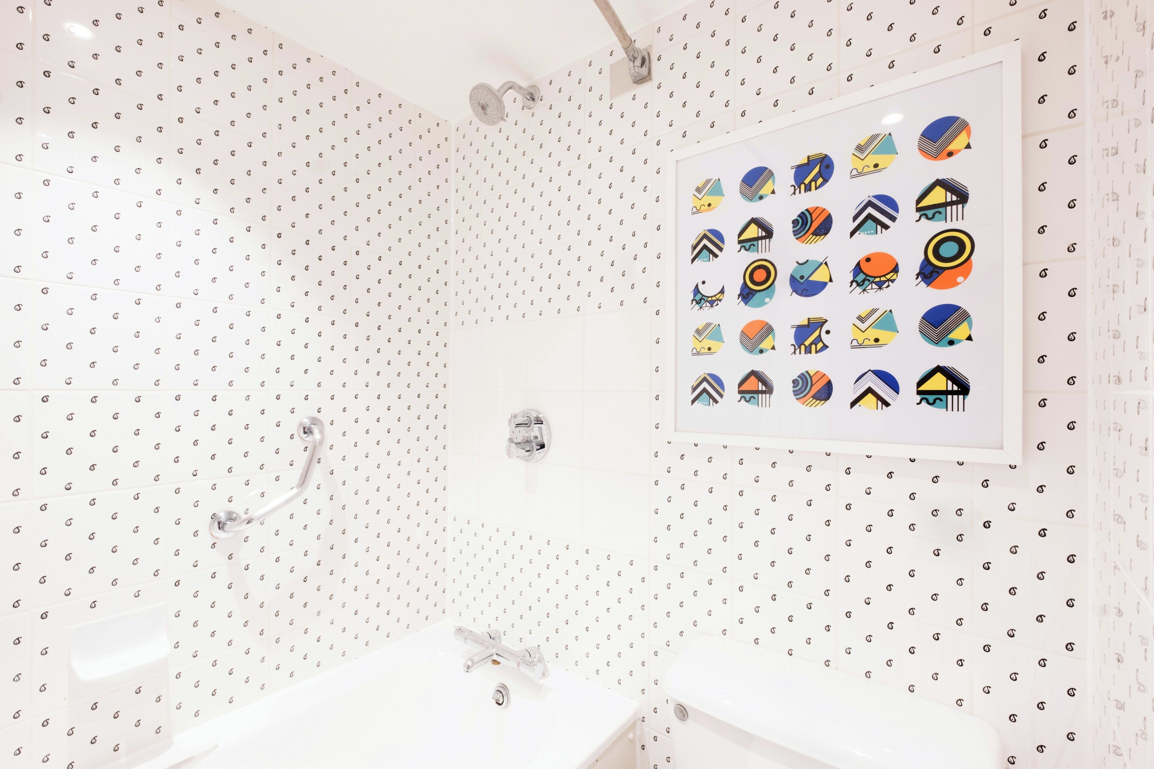 A bathroom with a shower, a sink, and a wall-mounted toilet.