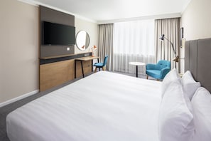 A hotel room with a large bed, a desk with a chair, a TV, and a view of the outdoors through the window. - Holiday Inn Coventry M6, Jct.2 by IHG (Coventry)