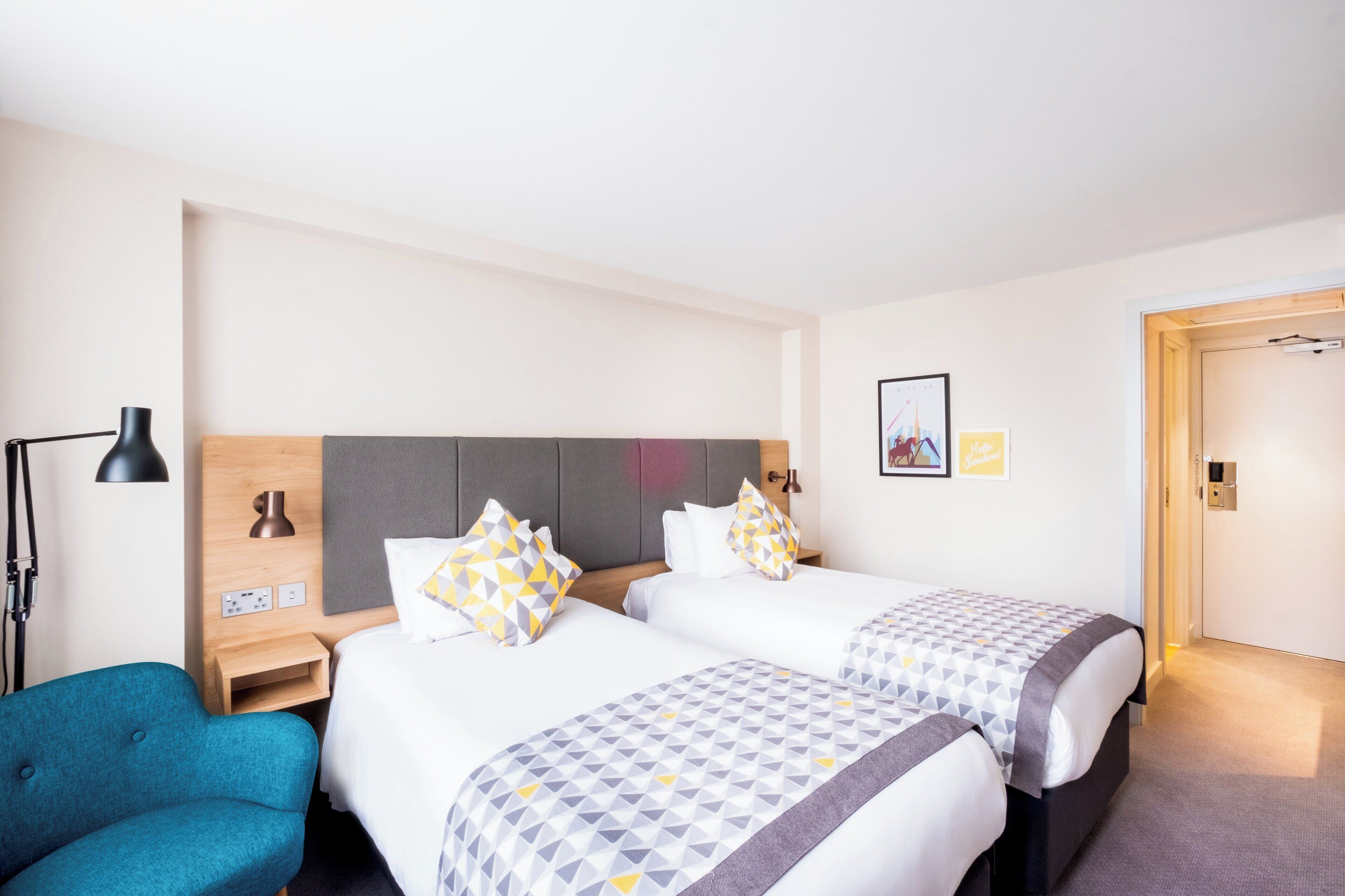 Habitación de hotel con dos camas, un escritorio, una silla y una puerta.