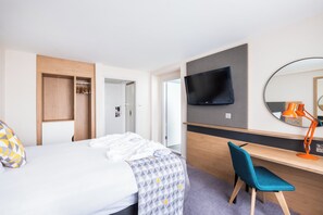 A hotel room with a bed, a desk, a chair, a television, and a mirror. - Holiday Inn Coventry M6, Jct.2 by IHG (Coventry)
