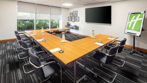 A conference room with a long table, black chairs, a projector screen, and framed pictures on the wall. - Holiday Inn Coventry M6, Jct.2 by IHG (Coventry)