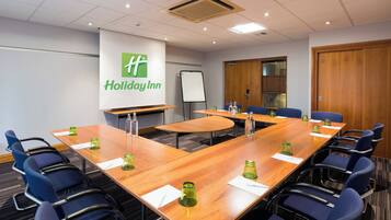A conference room with a large table, blue chairs, a whiteboard, and a Holiday Inn sign.