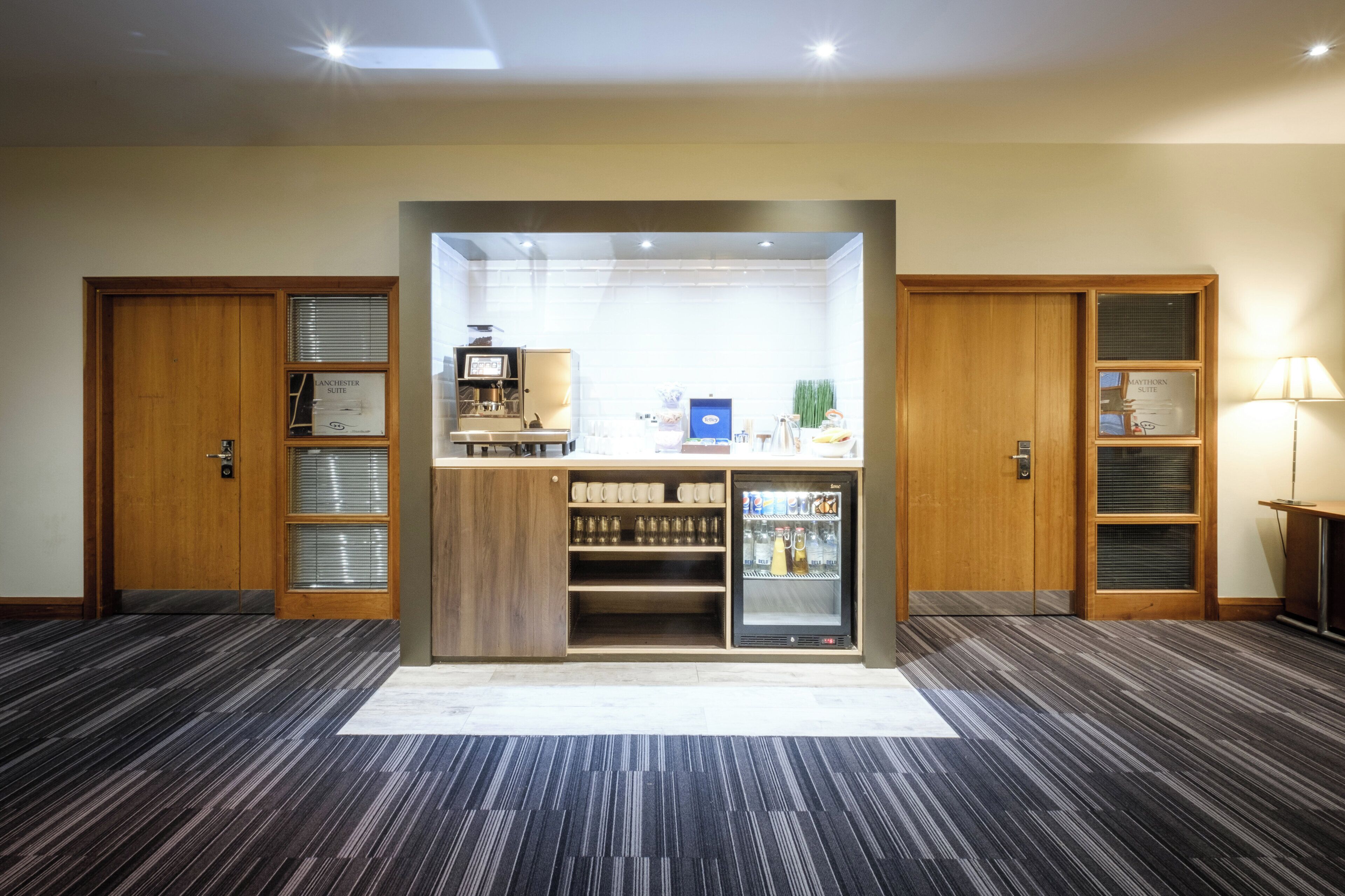 A hotel room with a minibar, a coffee machine, and a refrigerator.