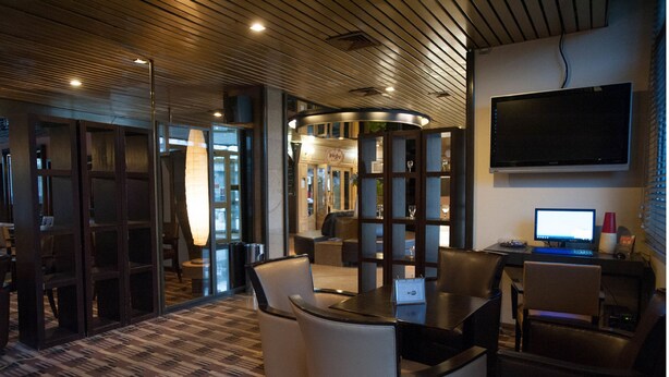 A modern office space with a curved seating area, a flat-screen TV, and a computer on a desk. - Median Paris Congres Hotel (Paris)