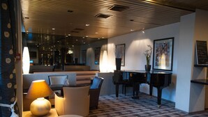 A modern lobby with a piano, seating area, and artwork on the walls. - Median Paris Congres Hotel (Paris)