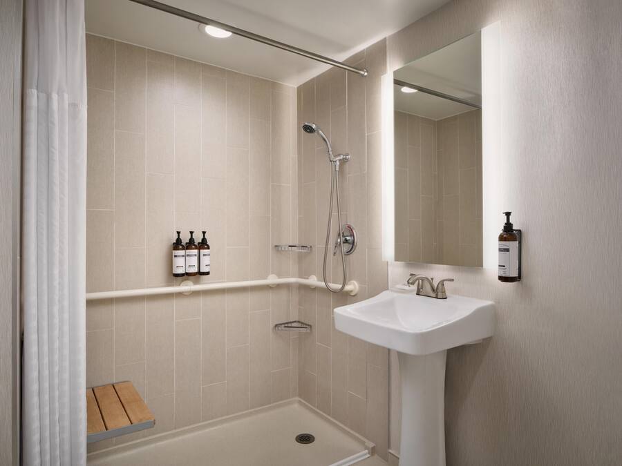 Un baño moderno con ducha, lavamanos y espejo.
