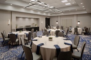 A conference room with round tables, chairs, and a carpeted floor.