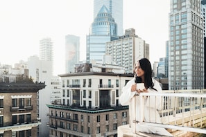 A person sitting on a balcony overlooking a cityscape with various buildings, including a prominent skyscraper. - Loews Regency New York Hotel (New York)