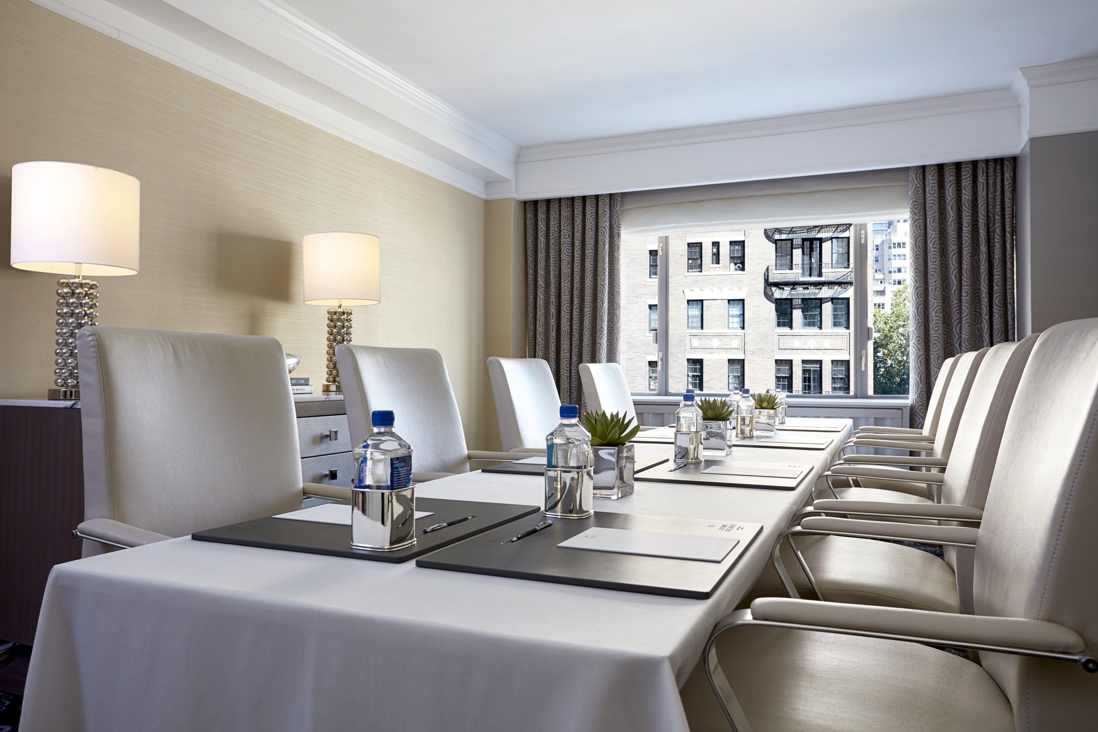 A conference room with a long table, multiple chairs, water bottles, and a laptop.
