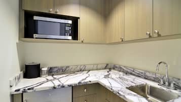 A kitchen with a built-in microwave, a sink, and marble countertops.
