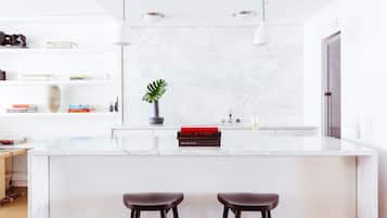 Una cocina moderna con encimera de mármol, dos taburetes de bar y una planta en maceta.