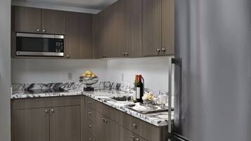Una cocina moderna con armarios de madera oscura, un refrigerador de acero inoxidable, un microondas y una encimera de mármol.