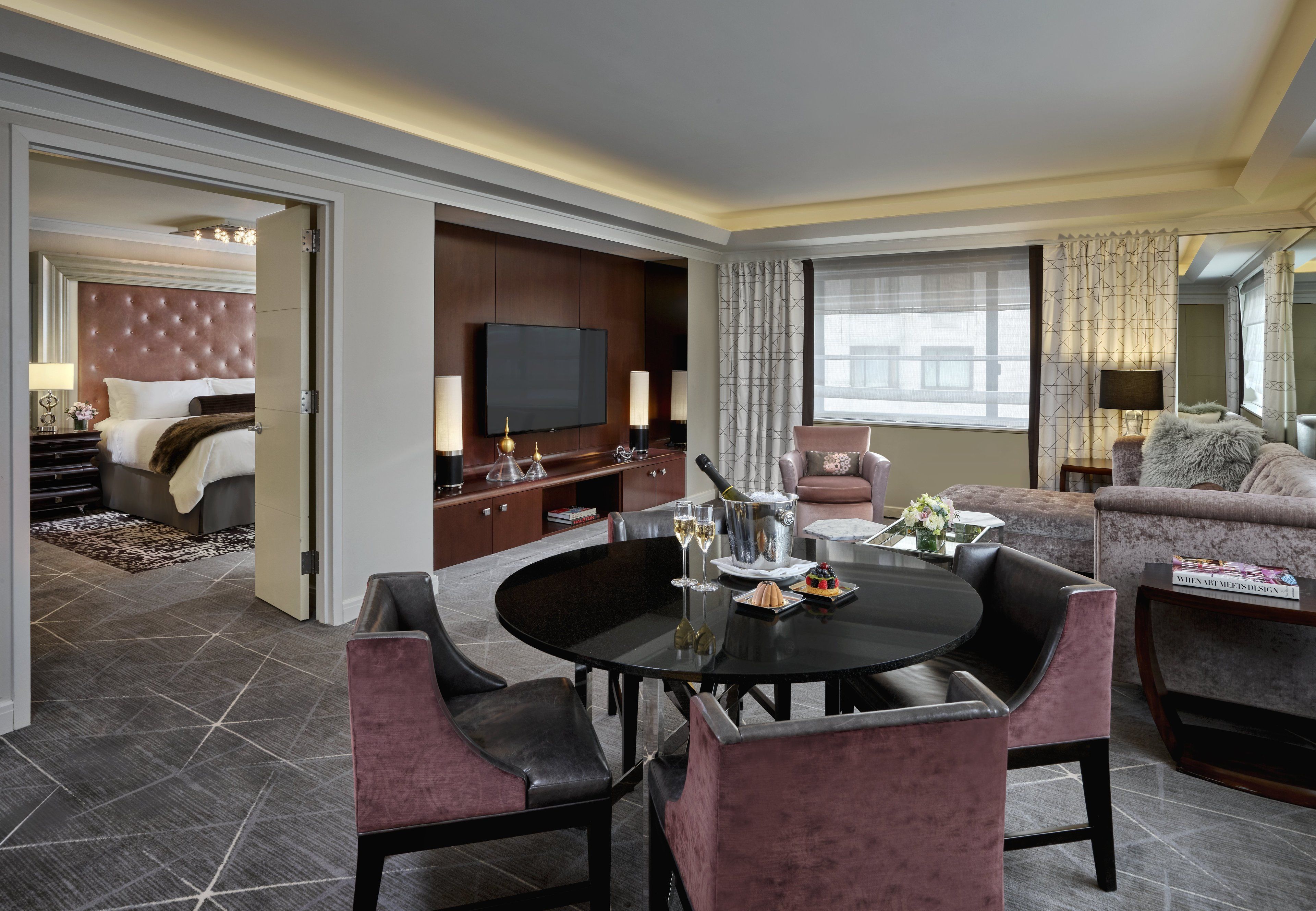 Ein Hotelzimmer mit Essbereich, Fernseher, Sofa und einem Bett mit Kopfteil.