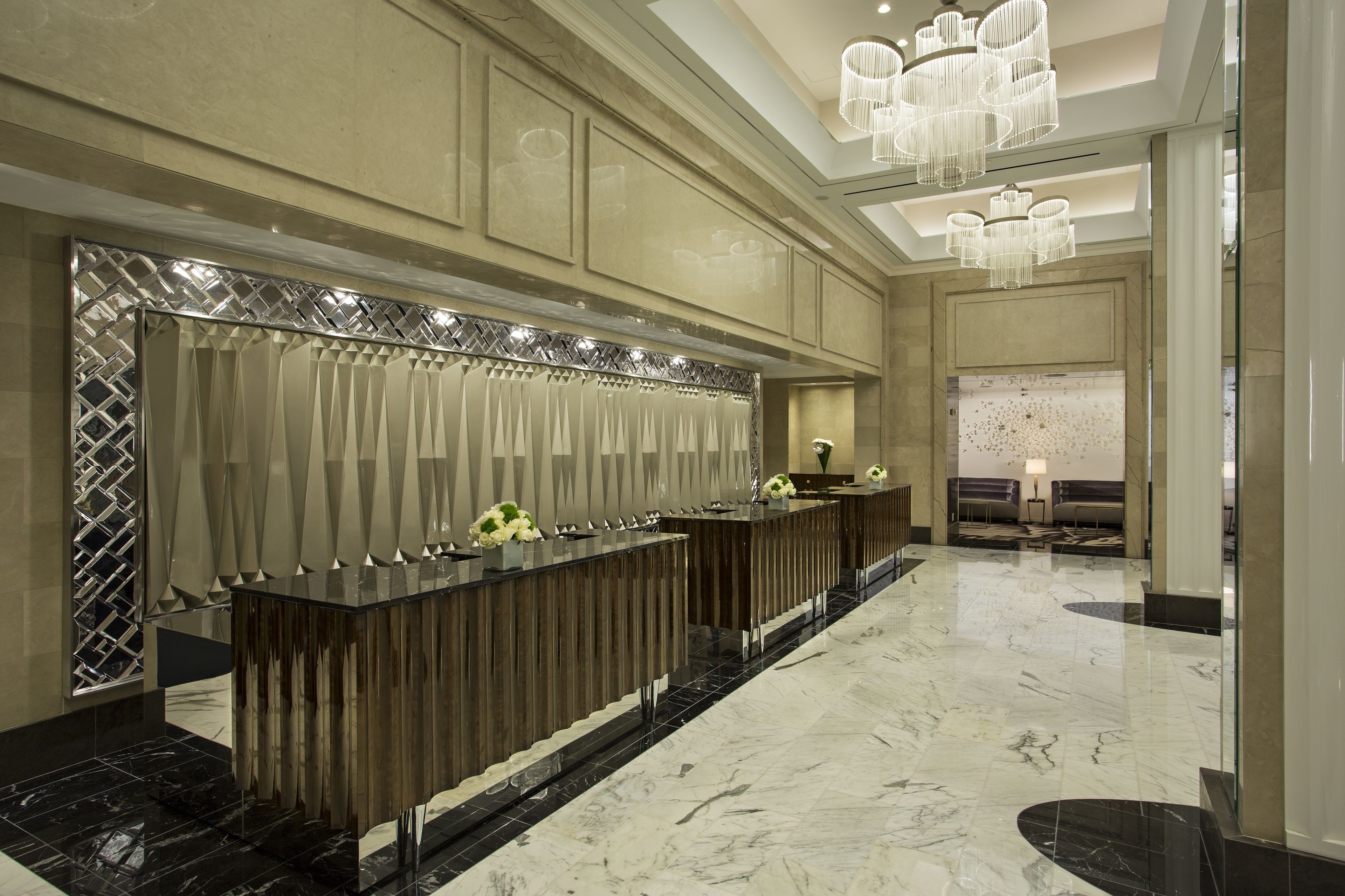A reception area with a marble floor, a reception desk, and a chandelier.
