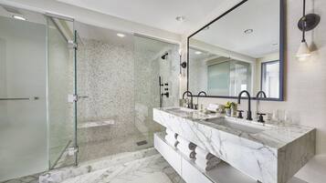 Une salle de bain moderne avec une douche à parois de verre, un grand miroir et un meuble-lavabo en marbre.