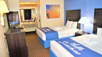 A hotel room with two beds, a TV, a desk, a mirror, and a painting on the wall.