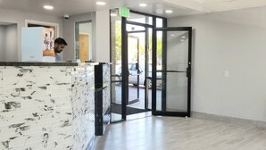A reception area with a marble-patterned counter, a glass door leading outside, and a tiled floor. - Days Inn by Wyndham Easley/Greenville/Clemson Area (Easley)