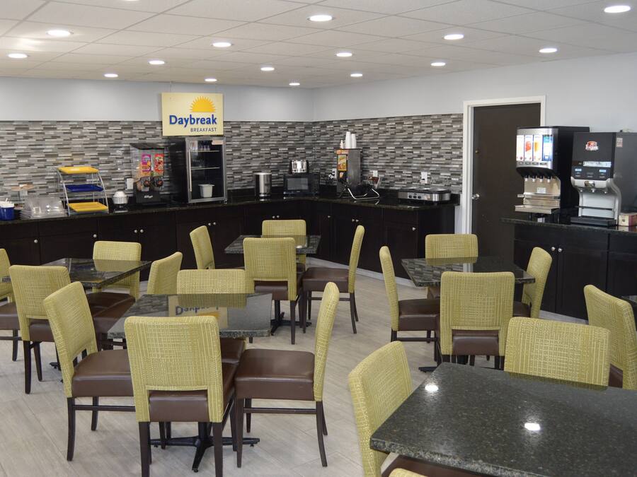 A Daybreak breakfast restaurant with multiple tables and chairs, a coffee machine, and a refrigerator.