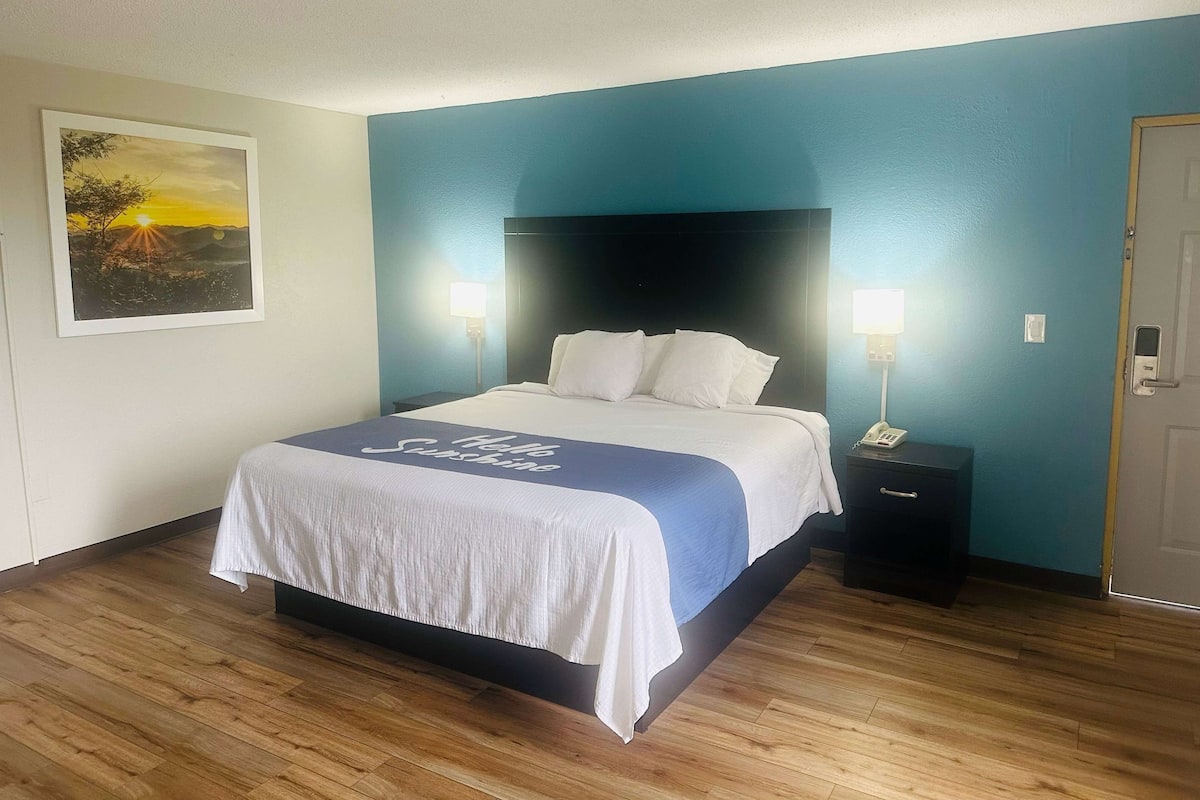 A neatly made bed with a white and blue bedspread, two bedside lamps, and a framed picture on the wall.