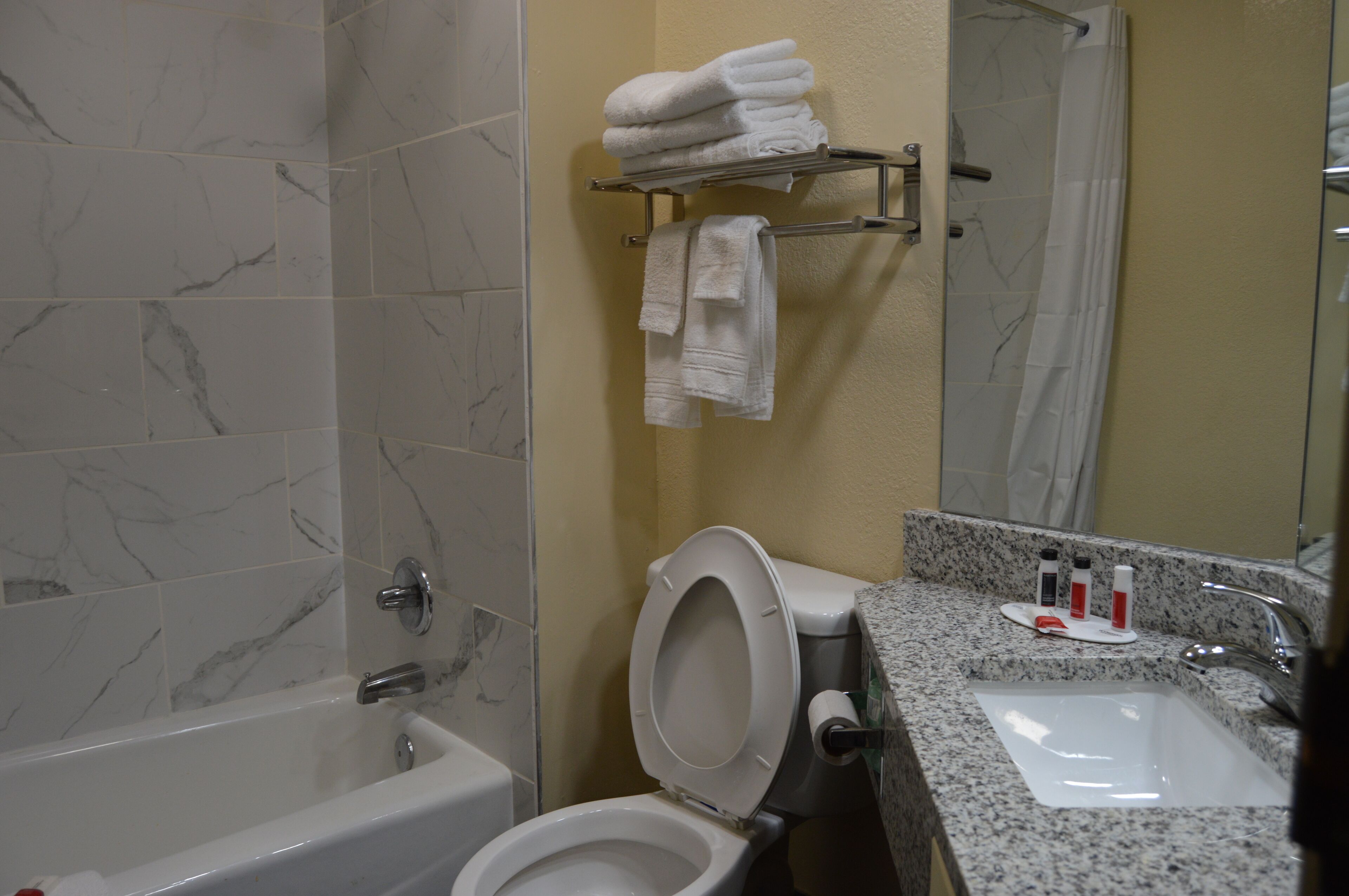 Un baño con bañera, inodoro, lavabo y toallero.