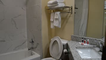 Un baño con bañera, inodoro, lavabo y toallero.