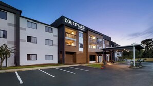 A Courtyard by Marriott hotel with a modern design, multiple balconies, and a covered parking area.