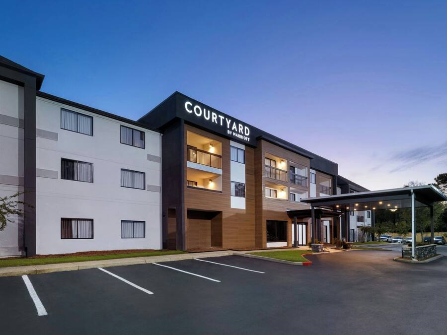 Um hotel Courtyard by Marriott com design moderno, várias varandas e área de estacionamento coberta.