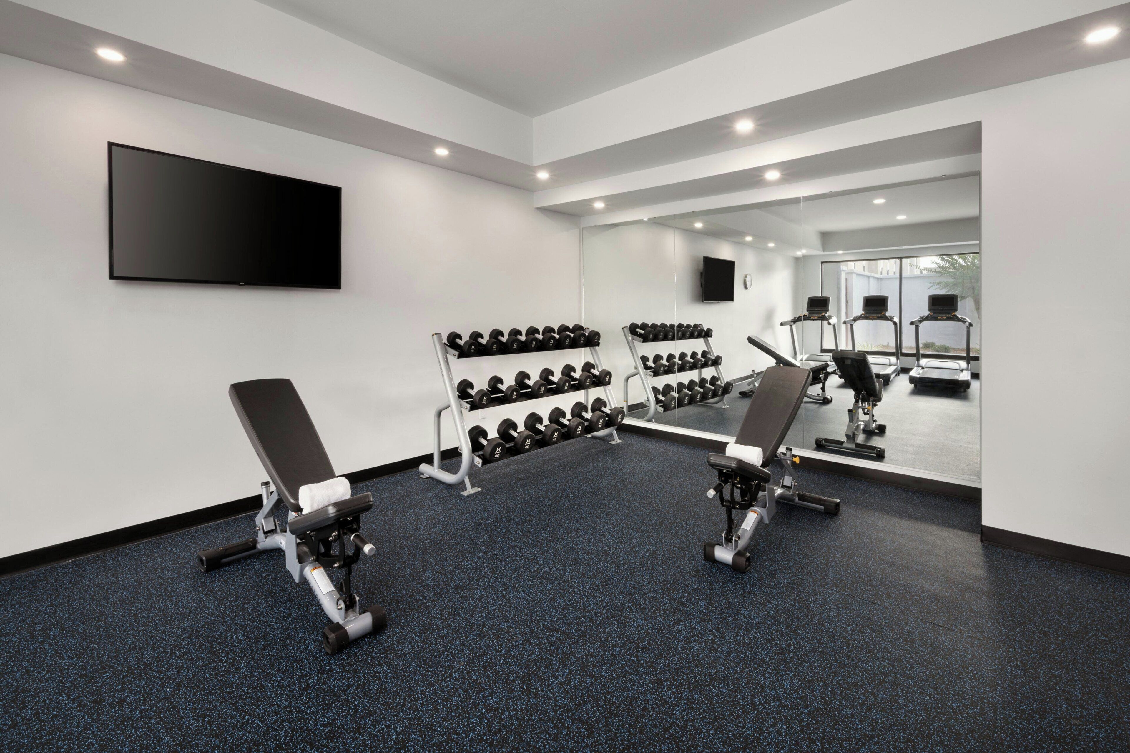 Une salle de sport moderne équipée de bancs de musculation, d’haltères et d’appareils de cardio-training.