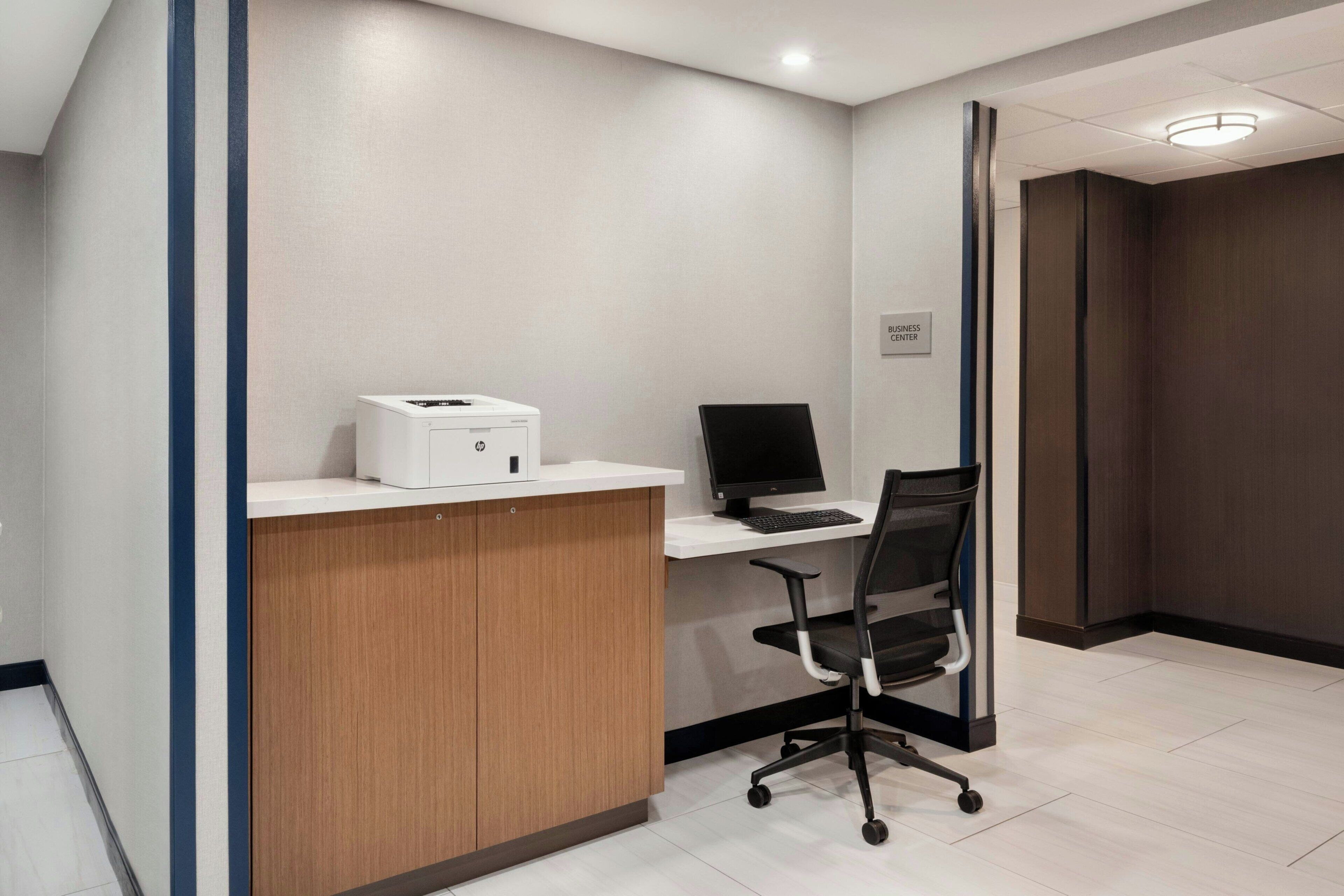 Un mostrador de recepción con una impresora, computadora y una silla de oficina en un espacio de trabajo moderno.